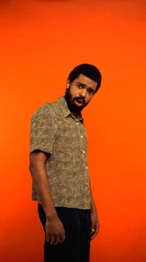 Şok olmuş sakallı ve portakallı Afro-Amerikan adamın dikey görüntüsü.