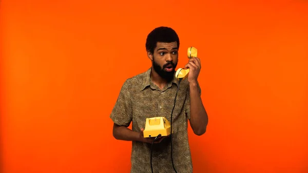 Chocado Afro Americano Homem Com Barba Segurando Telefone Retro Amarelo — Fotografia de Stock