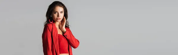 Young woman in red suit and earrings posing isolated on grey, banner — Stock Photo