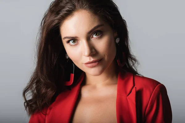 Junge Frau in rotem Anzug und Ohrringen blickt vereinzelt in die Kamera — Stockfoto