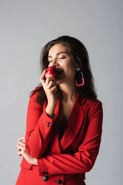 Felice donna in abito rosso mangiare mela fresca isolato su grigio — Foto stock