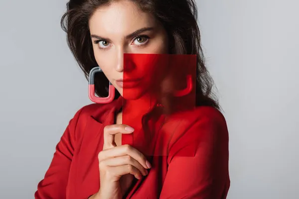 Jeune femme regardant caméra et tenant verre rouge isolé sur gris — Photo de stock