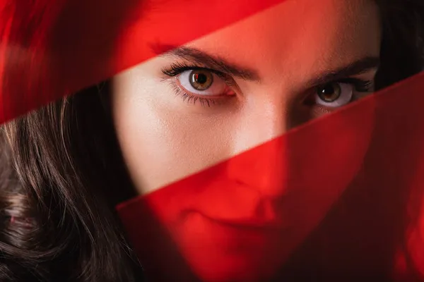 Close up of young woman looking at camera through red glass — Stock Photo