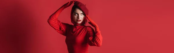 Young brunette woman in beret posing while looking away on red, banner — Stock Photo