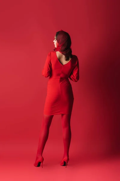 Full length of young woman in dress and headscarf standing on red — Stock Photo