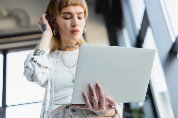 Unscharfe Sicht auf Geschäftsfrau mit Tätowierung, die im Büro am Laptop arbeitet — Stockfoto