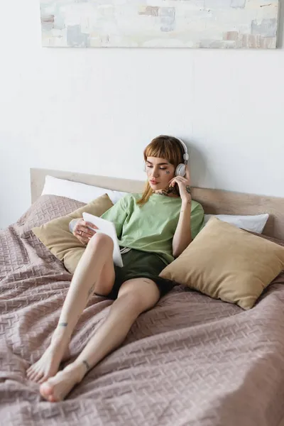 Barefoot tattooed woman with digital tablet listening webinar at home — Stock Photo