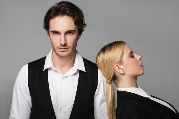 Blonde woman leaning on shoulder of elegant man looking at camera isolated on grey — Stock Photo