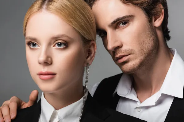 Young brunette man looking at camera near blonde woman isolated on grey — Stock Photo