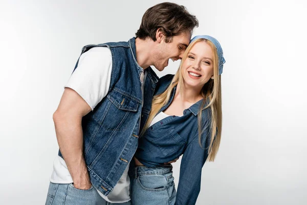 Hombre excitado con la mano en el bolsillo abrazando mujer alegre mirando a la cámara aislada en blanco - foto de stock