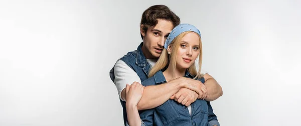 Young man embracing stylish woman in headband looking at camera isolated on white, banner — Stock Photo