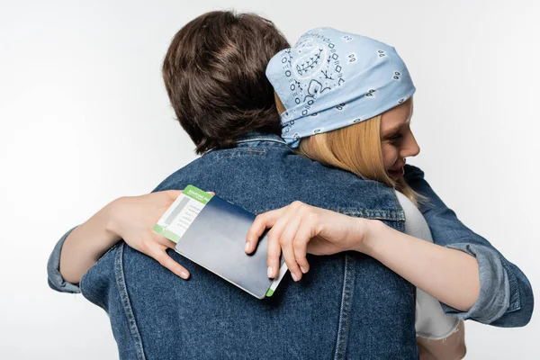 Femme heureuse dans le bandeau tenant passeport avec billet d'avion tout en embrassant l'homme isolé sur blanc — Photo de stock