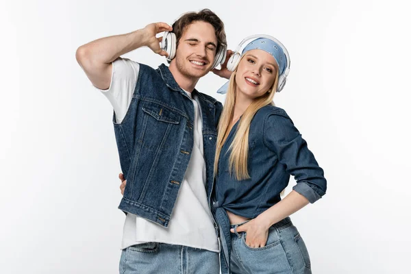 Happy young woman and man with closed eyes listening music in headphones isolated on white — Stock Photo