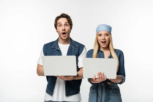 Casal surpreso com computadores olhando para a câmera isolada no branco — Fotografia de Stock