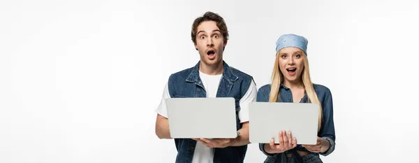 Casal espantado com laptops olhando para câmera isolada em branco, banner — Fotografia de Stock