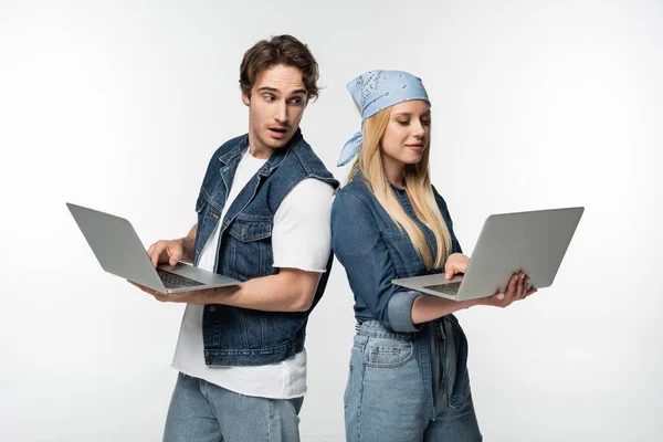 Curious man looking at laptop in hands of girlfriend isolated on white — Stock Photo