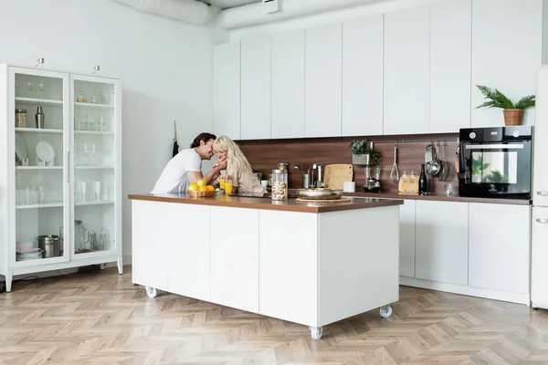 Homem feliz abraçando alegre namorada na cozinha — Fotografia de Stock