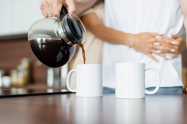 Обрезанный вид человека, наливающего кофе в чашку — стоковое фото