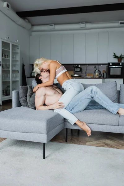 Femme sexy dans crop top baisers avec homme torse nu dans le salon — Photo de stock