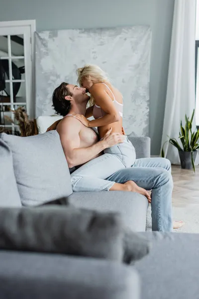 Side view of cheerful couple kissing on couch — Stock Photo