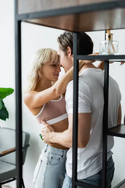 Femme heureuse étreignant l'homme près de rack dans le salon — Photo de stock