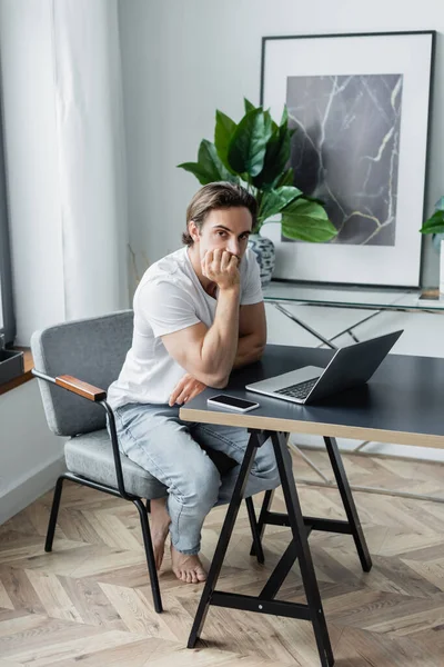 Freelancer entediado sentado na mesa com gadgets — Fotografia de Stock