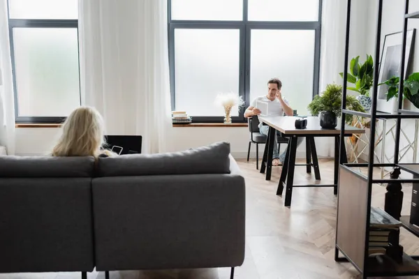 Femme blonde en utilisant des gadgets avec écran blanc près du petit ami avec tablette numérique assis au bureau — Photo de stock