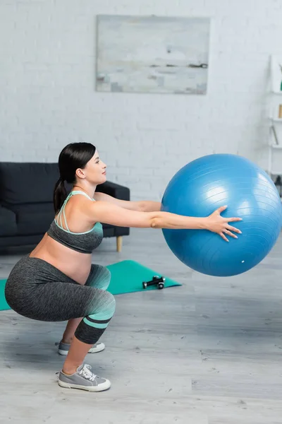 Side view of pregnant woman doing sit ups with fitness ball at home — Stock Photo