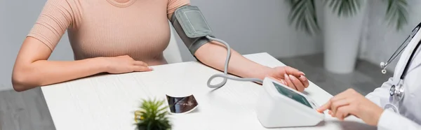 Partial view of doctor measuring blood pressure of pregnant woman near ultrasound scan on desk, banner — Stock Photo