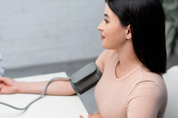 Morena mujer midiendo la presión arterial con tonómetro en la clínica - foto de stock