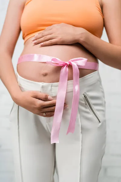 Vista parcial de la joven embarazada con cinta de satén en el vientre — Stock Photo