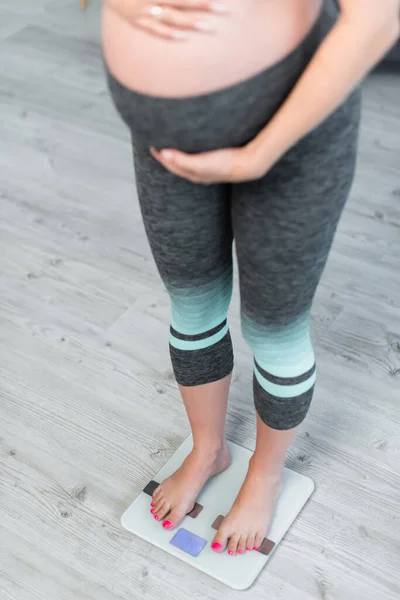 Обрезанный вид размытой беременной женщины, измеряющей вес тела на весах пола — стоковое фото