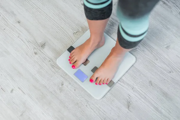 Vista parcial de la mujer descalza que mide el peso corporal en básculas de piso - foto de stock