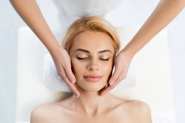 Вид зверху масажиста робить масаж обличчя блондинки клієнт — стокове фото