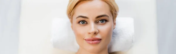 Top view of blonde client lying on massage table in spa center, banner — Stock Photo