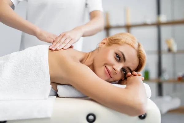 Massaggiatore che fa massaggio alle spalle al cliente felice sul tavolo da massaggio — Foto stock