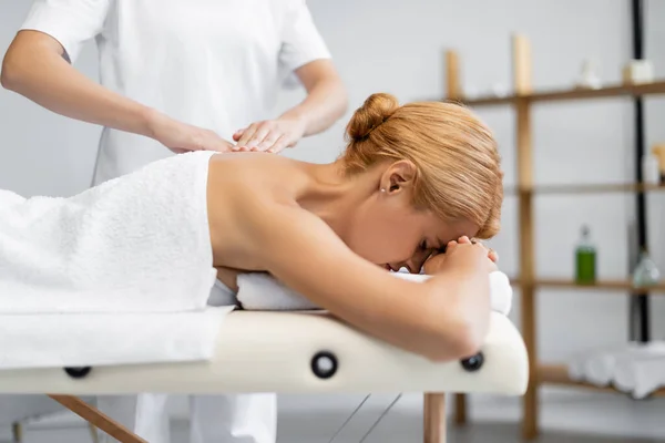 Masajista profesional haciendo masaje a cliente rubio - foto de stock