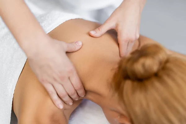 Cropped view of masseur doing shoulder massage to blonde client — Stock Photo