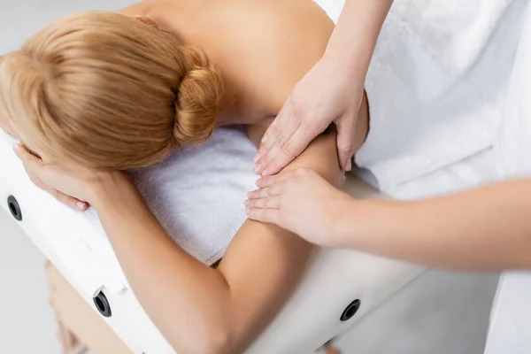 Massaggiatore facendo massaggio alle spalle al cliente biondo con gli occhi chiusi — Foto stock