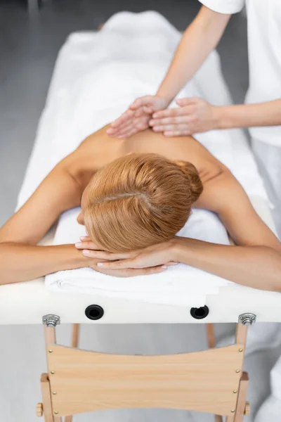 Massagista fazendo massagem para mulher loira na mesa de massagem — Fotografia de Stock