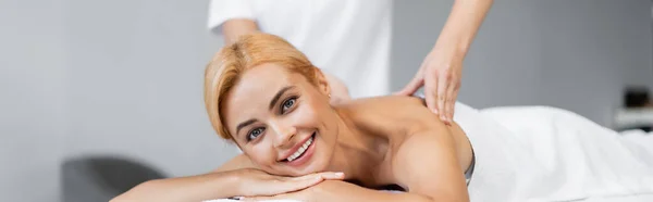 Masajista haciendo masaje de hombros al cliente sonriente en el centro de spa, pancarta - foto de stock