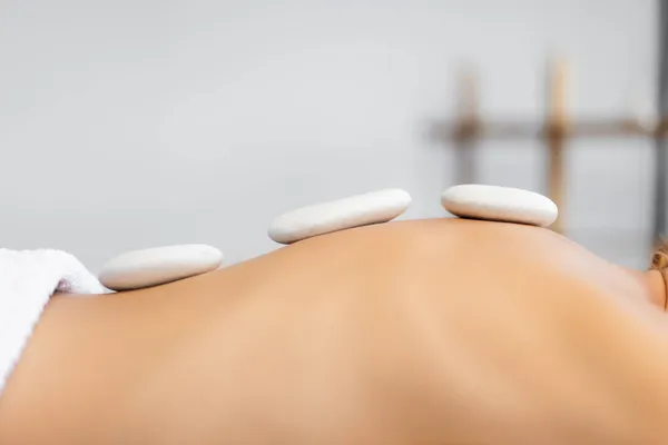 Cropped view of woman receiving hot stone massage in spa center — Stock Photo