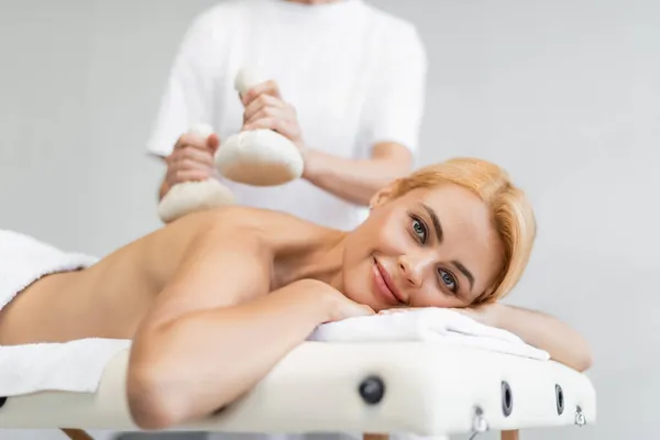 Cheerful woman receiving massage with herbal bags in spa center — Stock Photo