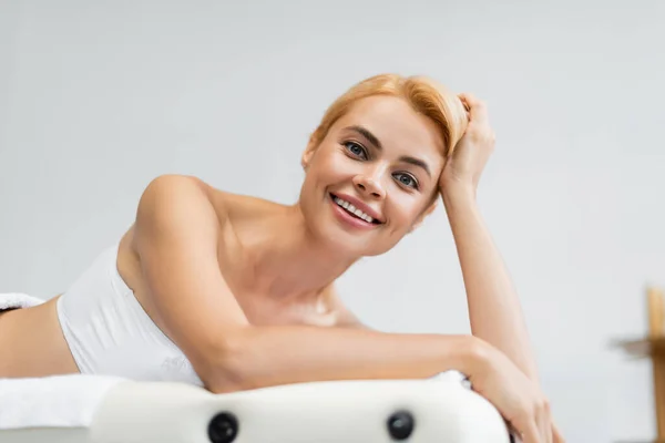 Веселий блондинка клієнт лежить на масажному столі — стокове фото
