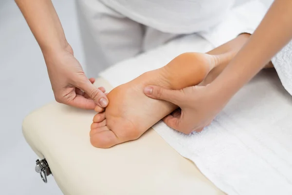 Blick aus der Vogelperspektive auf den professionellen Masseur, der dem Kunden im Wellness-Center eine Fußmassage anbietet — Stockfoto