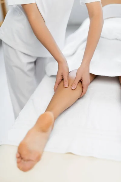 Vista cortada de massagista fazendo massagem nos pés para mulher desfocada no centro de spa — Fotografia de Stock