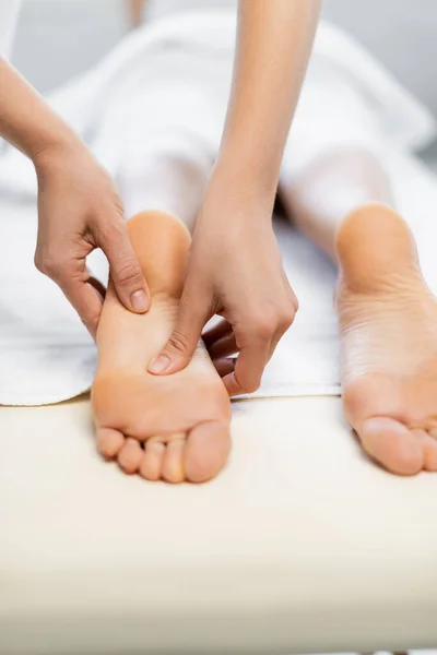 Vista cortada do massagista fazendo massagem nos pés para a mulher na mesa de massagem — Fotografia de Stock