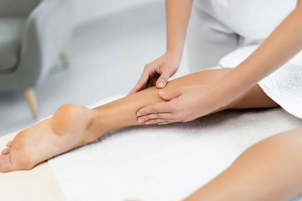 Partial view of masseur doing foot massage to client on massage table — Stock Photo