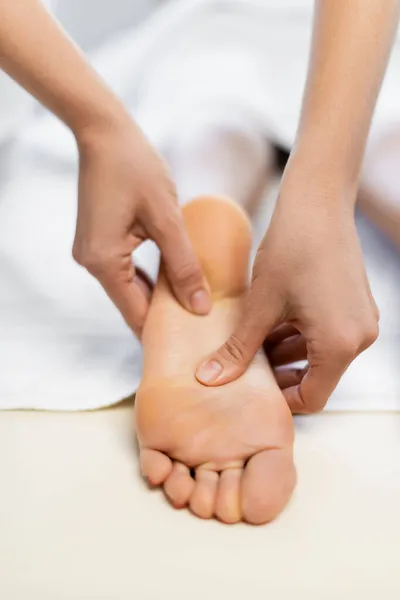 Vista cortada de massagista fazendo massagem nos pés para o cliente — Fotografia de Stock