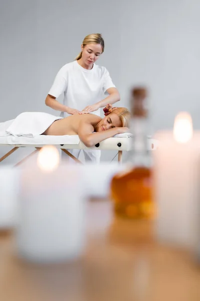 Masseur doing massage to client in spa center with blurred foreground — Stock Photo